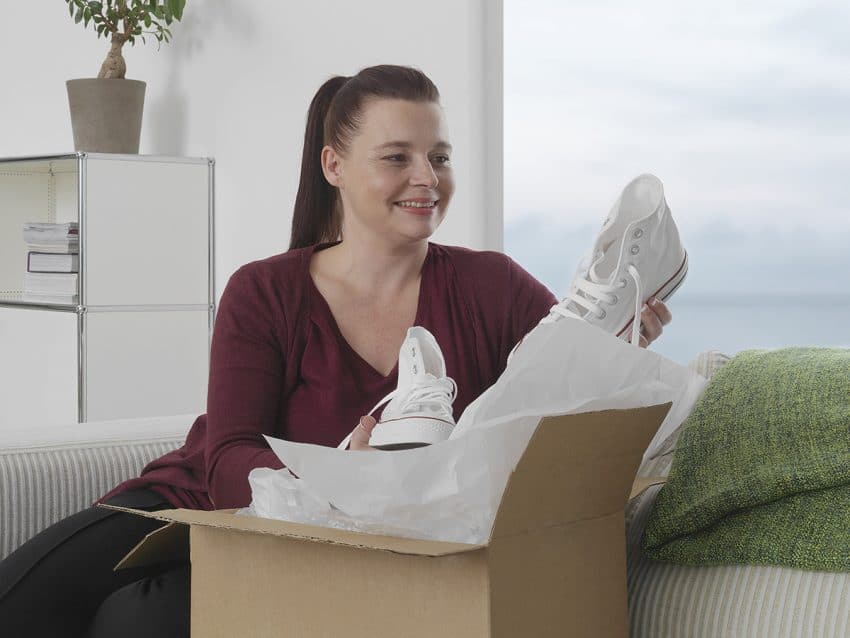 Kvinna som öppnar ett paket med skor